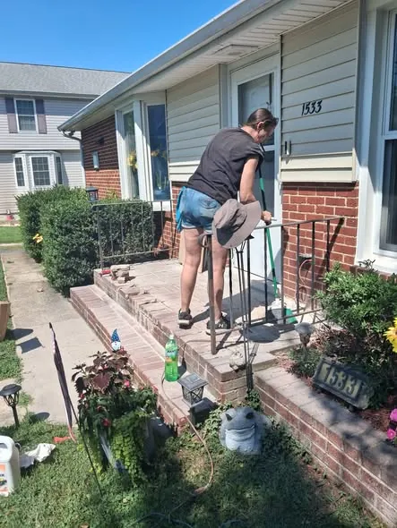Working on the handrail and front steps of a brick porch.