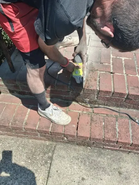 Grinding out old mortar joints along a brick garden wall.